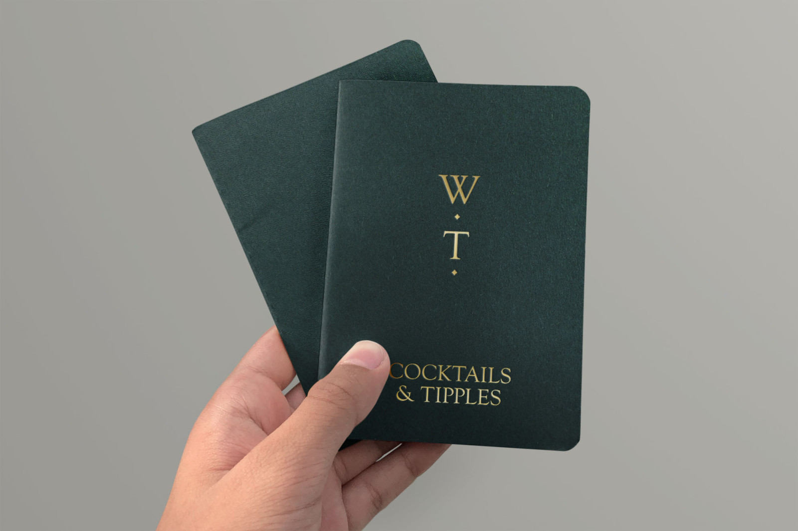 Dark green, pocket sized cocktail menu cover with gold foil monogram and text, by BusbyWebb